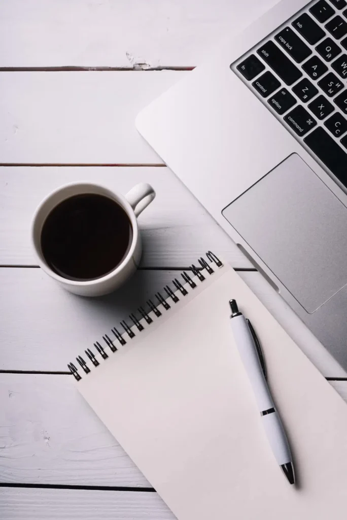 espace de travail vu d'en haut avec un mug de café, un bloc notes vierge et un ordinateur portable